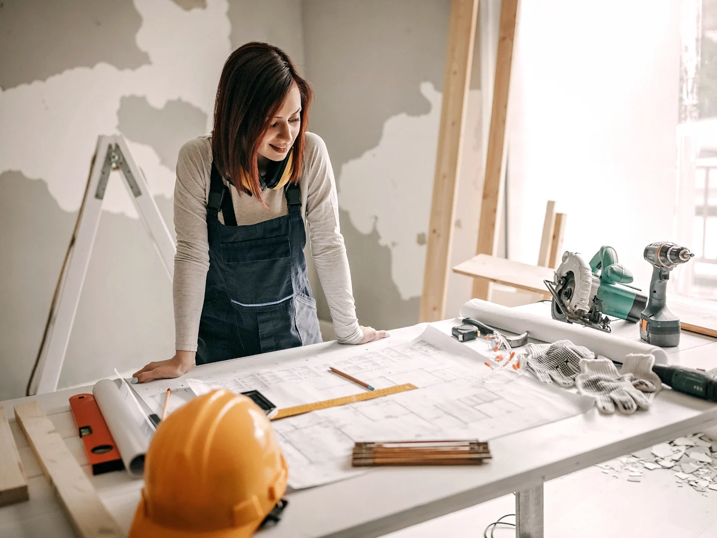 Adviseur bekijkt renovatieplannen op een werktafel in een woning in renovatie