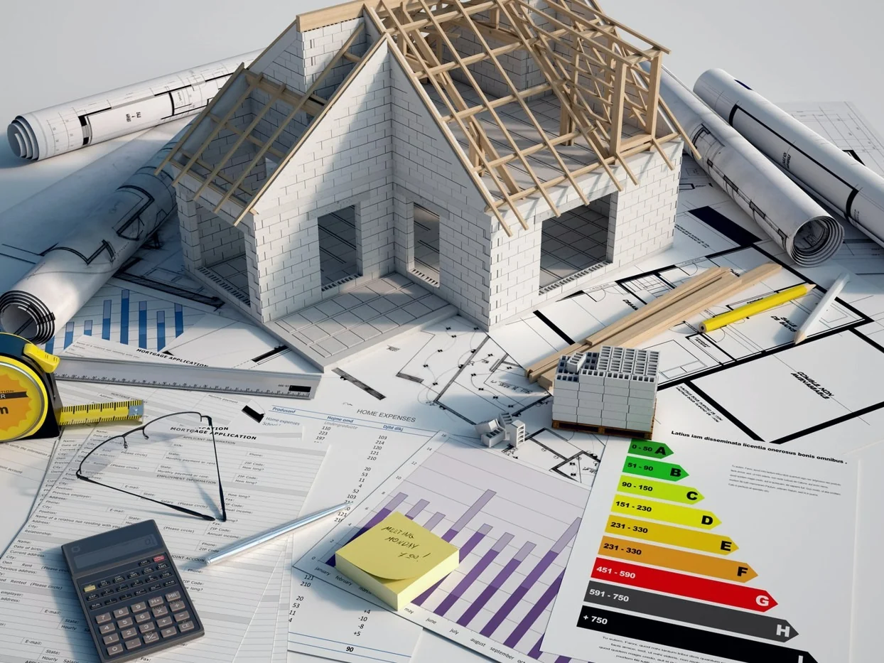 Bouwplannen, maquette van een woning en berekeningen op een bureau voor een EPB-dossier