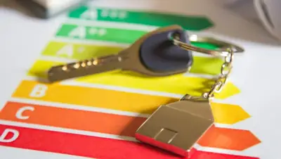 Sleutel met sleutelhanger in de vorm van een huisje op een gekleurde energielabelschaal van A+++ tot D